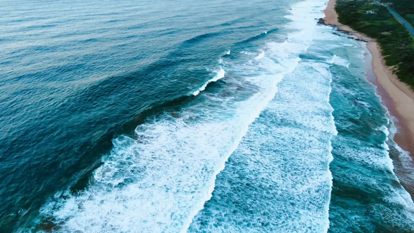 Aerial ocean waves rolling into shore